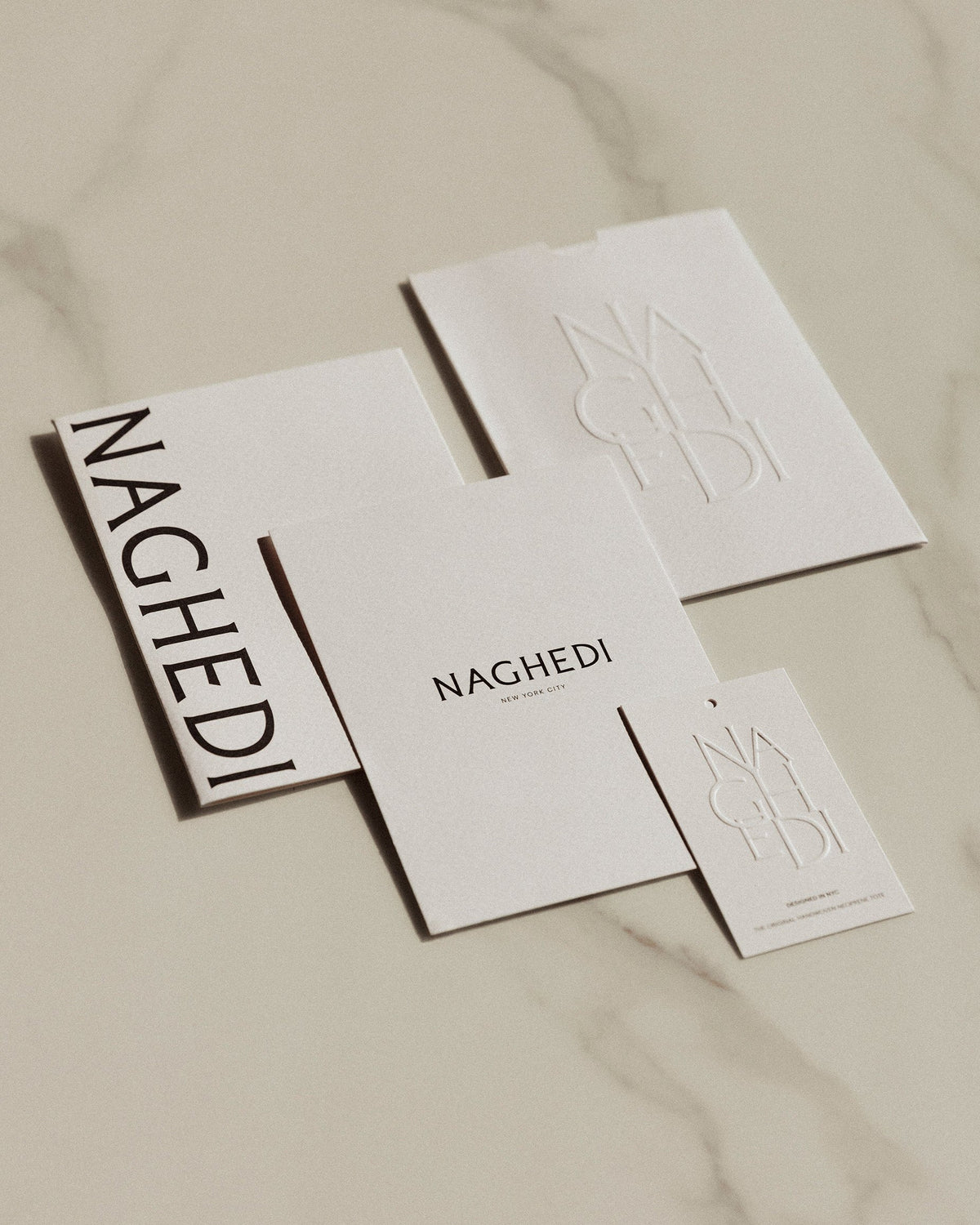 ベージュの布地を背景にしたNaghedi（ナゲディ）のブランドカード